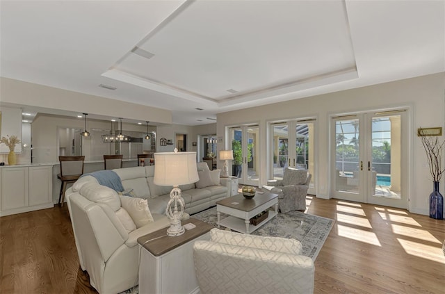 living room with a tray ceiling, french doors, and hardwood / wood-style flooring