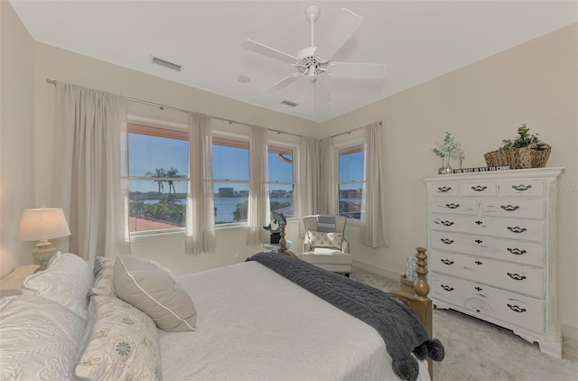 carpeted bedroom with ceiling fan and a water view