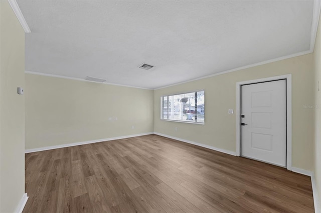 empty room with a textured ceiling, wood-type flooring, and ornamental molding