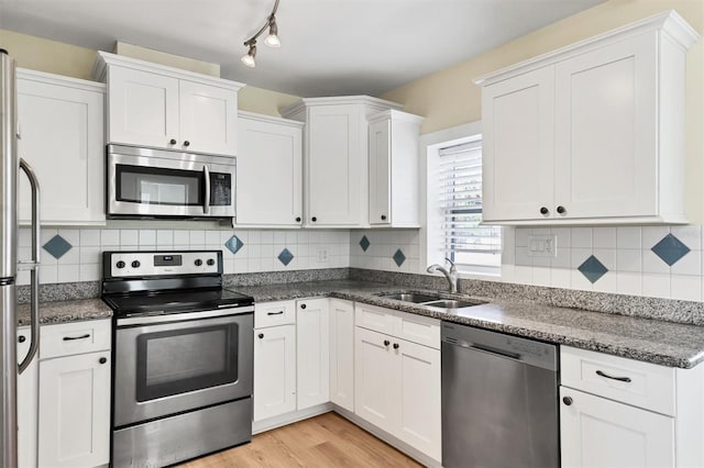 kitchen with white cabinetry, sink, stainless steel appliances, tasteful backsplash, and light hardwood / wood-style flooring