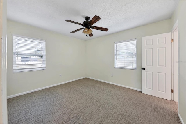 carpeted spare room with a textured ceiling, ceiling fan, and a healthy amount of sunlight