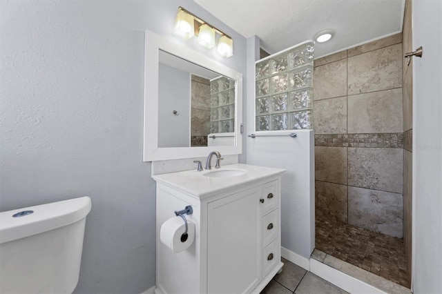 bathroom featuring tiled shower, vanity, tile patterned flooring, and toilet