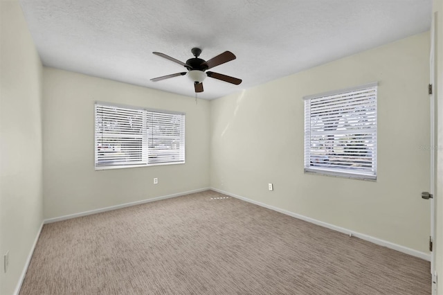 spare room featuring ceiling fan, light colored carpet, and a textured ceiling