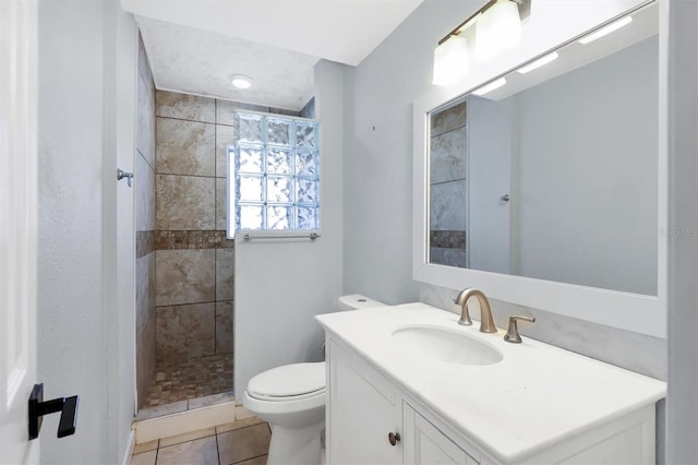 bathroom with tile patterned floors, vanity, a tile shower, and toilet