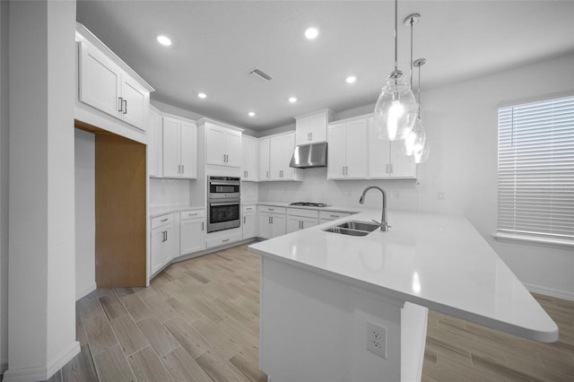 kitchen featuring sink, kitchen peninsula, decorative backsplash, decorative light fixtures, and white cabinetry