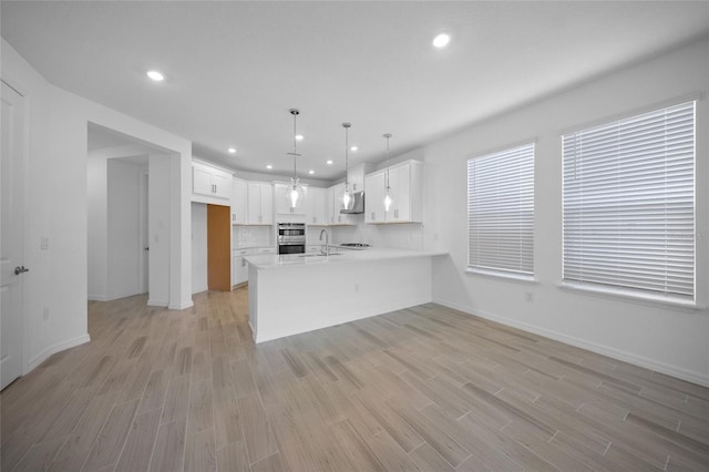 kitchen with decorative light fixtures, white cabinetry, sink, and kitchen peninsula