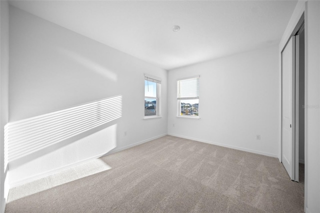 unfurnished bedroom featuring light carpet and a closet