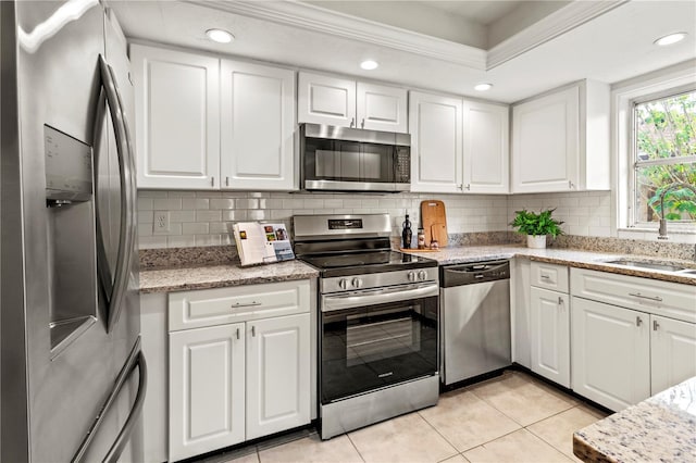 kitchen featuring white cabinets, sink, decorative backsplash, light tile patterned floors, and stainless steel appliances