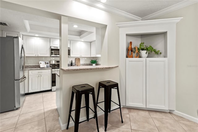 kitchen featuring a breakfast bar area, kitchen peninsula, white cabinetry, and appliances with stainless steel finishes