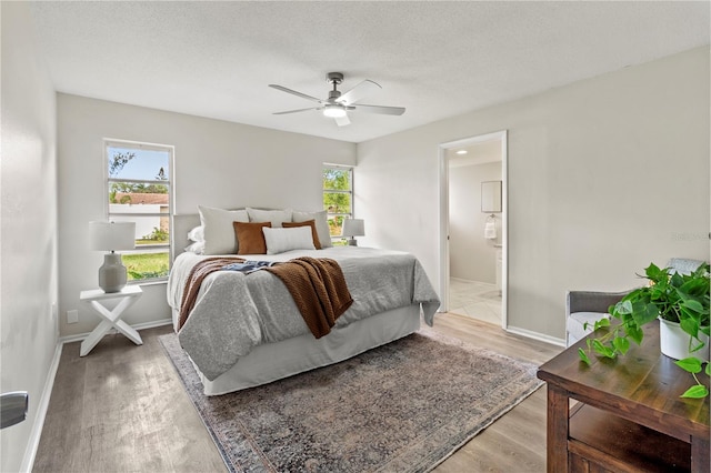 bedroom featuring ensuite bath, ceiling fan, hardwood / wood-style floors, and a textured ceiling