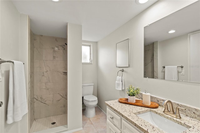 bathroom featuring a tile shower, tile patterned floors, vanity, and toilet