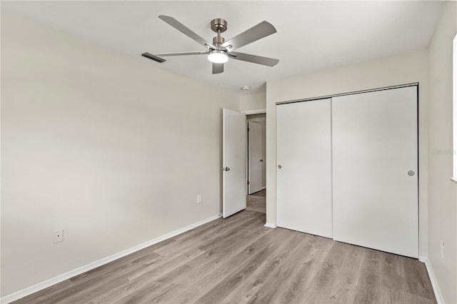 unfurnished bedroom with ceiling fan, light wood-type flooring, and a closet