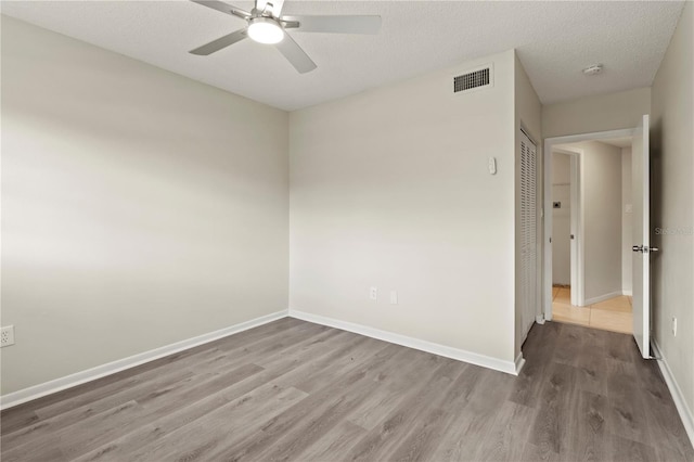 unfurnished room featuring hardwood / wood-style flooring, ceiling fan, and a textured ceiling