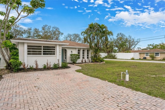 ranch-style house with fence, a front lawn, and stucco siding