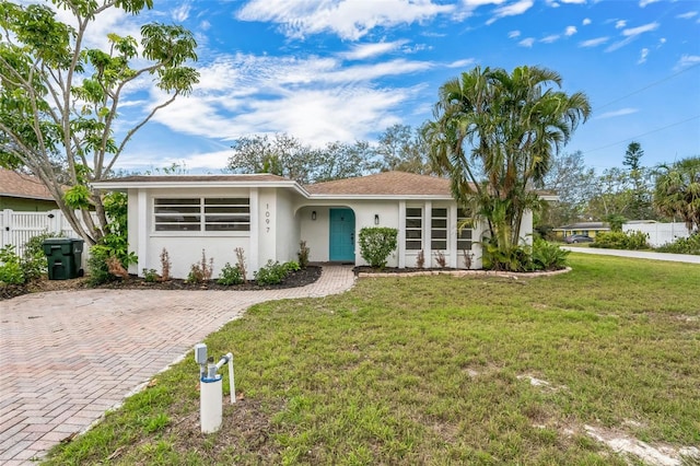 ranch-style house with a front yard, fence, and stucco siding