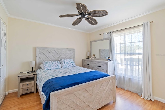 bedroom featuring ceiling fan, light wood-type flooring, crown molding, and a closet