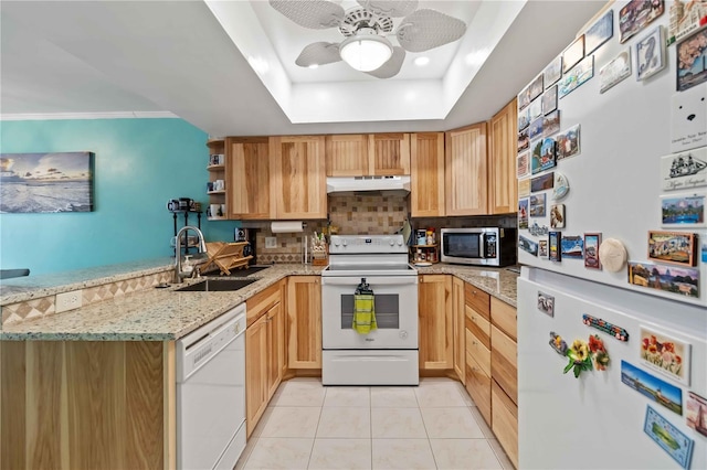 kitchen with ceiling fan, sink, light stone countertops, a raised ceiling, and white appliances