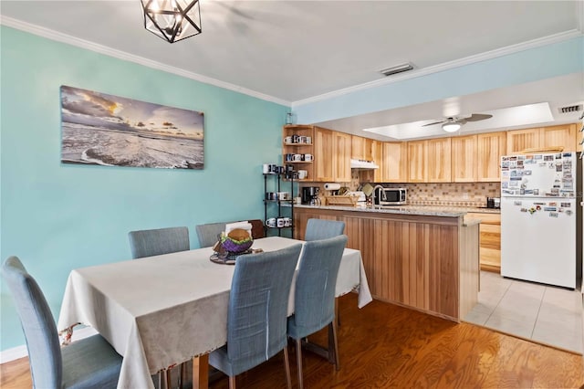 dining space featuring ceiling fan with notable chandelier, light wood-type flooring, and ornamental molding