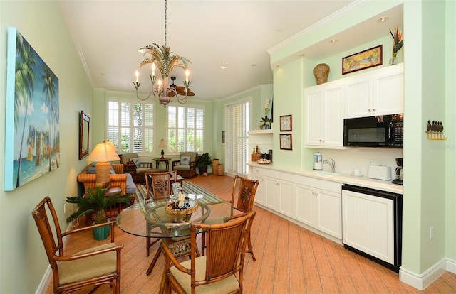 dining room with sink, light hardwood / wood-style floors, crown molding, and a notable chandelier