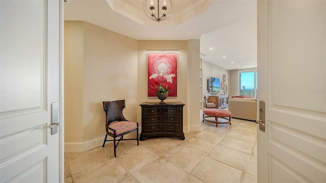 sitting room featuring a notable chandelier, a raised ceiling, and light tile patterned floors