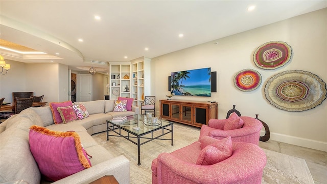 living room with built in shelves and a raised ceiling