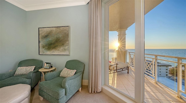 living area featuring carpet flooring, a water view, crown molding, and decorative columns