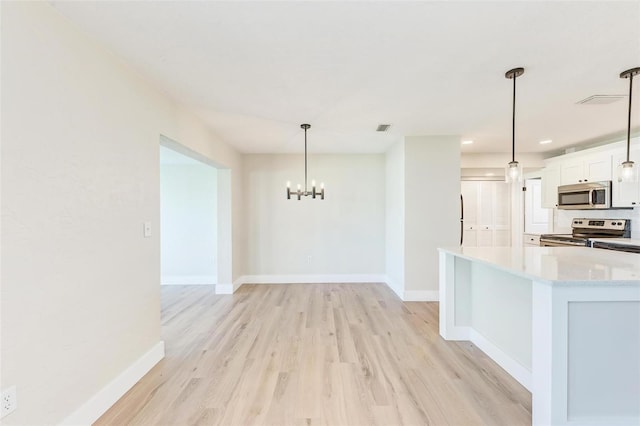 kitchen with white cabinets, light wood-type flooring, stainless steel appliances, and hanging light fixtures