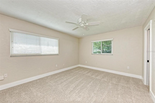 carpeted empty room with ceiling fan and a textured ceiling