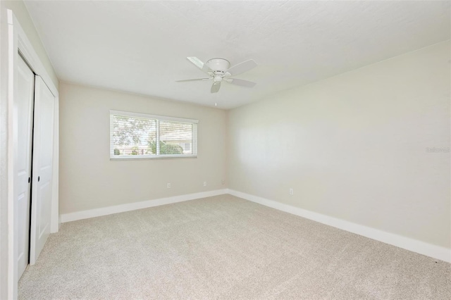 unfurnished bedroom featuring light carpet, a closet, and ceiling fan