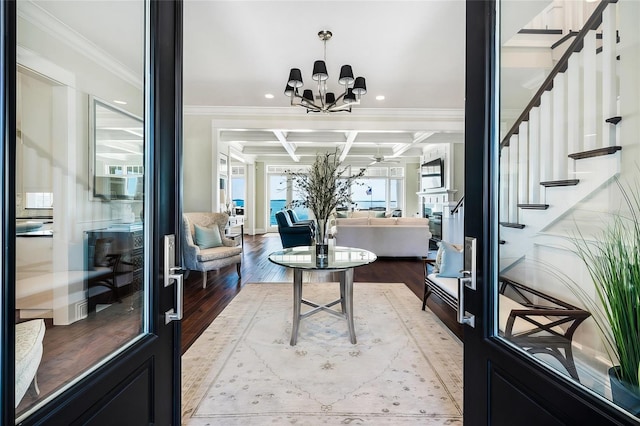 foyer with beam ceiling, coffered ceiling, crown molding, hardwood / wood-style floors, and a chandelier