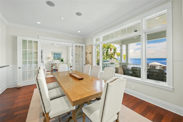 dining area featuring ceiling fan, french doors, dark hardwood / wood-style flooring, crown molding, and a water view