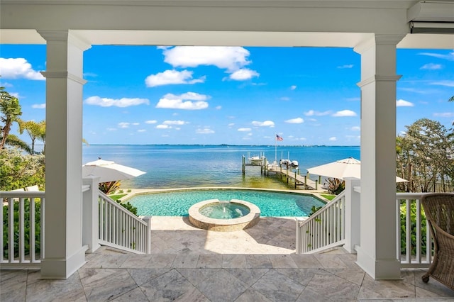 view of swimming pool with a water view, a dock, and an in ground hot tub