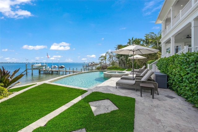 view of swimming pool with a lawn, a water view, a boat dock, an in ground hot tub, and a patio area