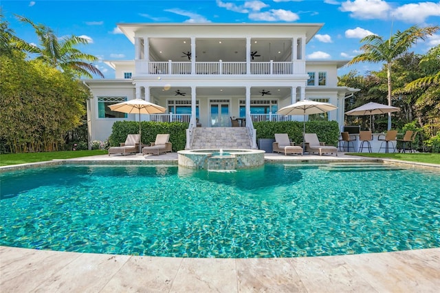 back of property with a patio area, a balcony, and a pool with hot tub