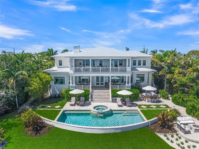 back of property featuring a swimming pool with hot tub, a balcony, and a patio