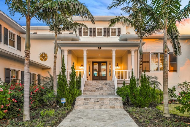 exterior entry at dusk featuring french doors and a porch