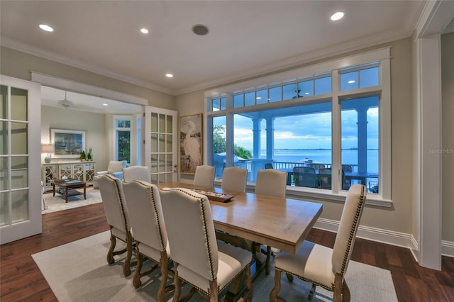 dining room with french doors, dark hardwood / wood-style flooring, a water view, and ornamental molding