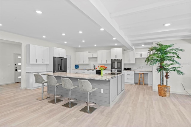 kitchen with a breakfast bar, a large island with sink, white cabinetry, and high quality fridge