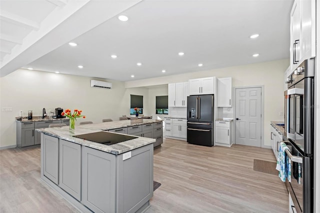 kitchen featuring black appliances, a large island, white cabinets, and light wood-style floors