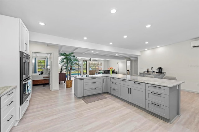 kitchen featuring gray cabinets, light hardwood / wood-style flooring, and light stone counters