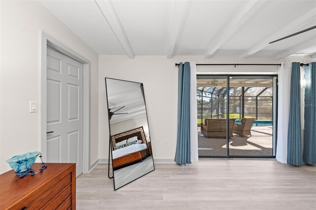 doorway with beamed ceiling, light wood-type flooring, and a sunroom