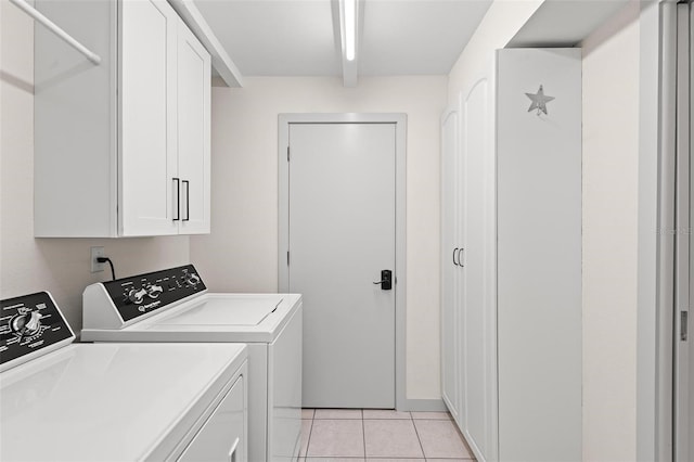 clothes washing area with light tile patterned floors, washing machine and clothes dryer, and cabinet space