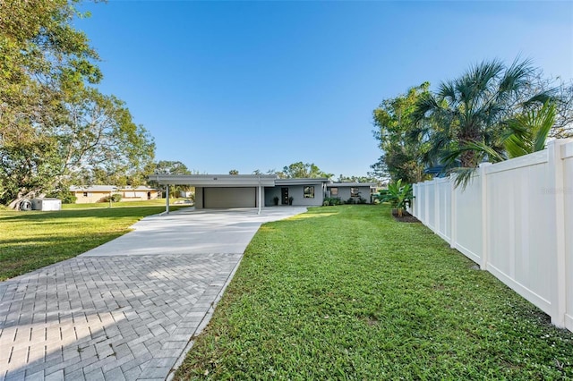 view of front of house featuring an attached carport, fence, driveway, and a front lawn