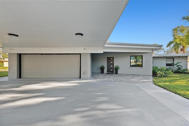 view of front facade with a garage, concrete driveway, and stucco siding