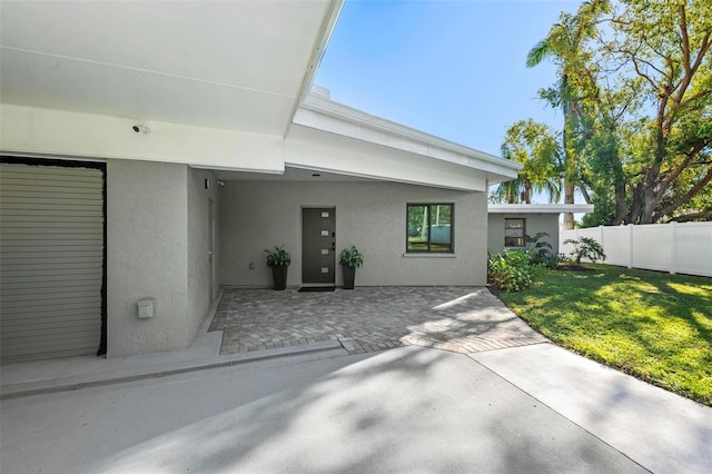 view of front of home with a patio, a front lawn, fence, and stucco siding