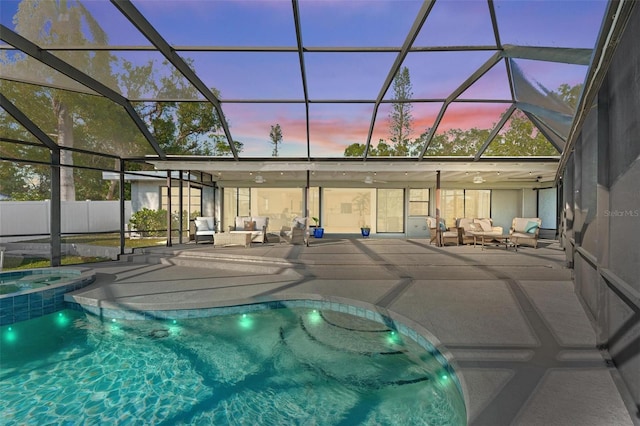 608 69th Ave W, Bradenton, FL 34207 - pool at dusk featuring an outdoor living space, a patio area, a pool with connected hot tub, and glass enclosure