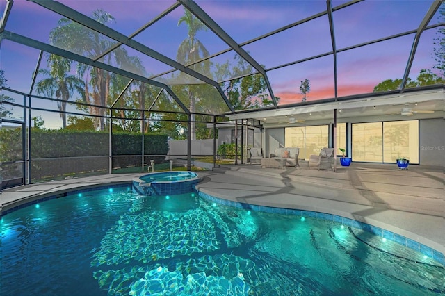 pool at dusk with a lanai, an in ground hot tub, and a patio