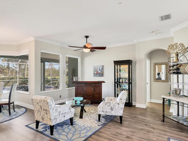 living room featuring ceiling fan, wood-type flooring, and ornamental molding