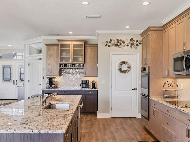 kitchen with sink, dark hardwood / wood-style floors, ornamental molding, appliances with stainless steel finishes, and light stone counters