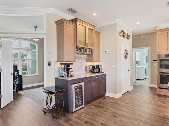 kitchen with washer / dryer, double oven, beverage cooler, and wood-type flooring